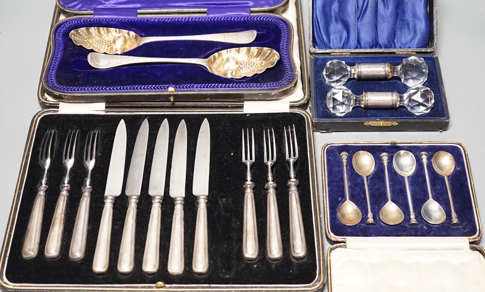 Two 18th century silver 'berry' spoons in associated case and three other cased sets including, pair of silver mounted glass knife rests, a cased set of six seal top coffee spoons and a part set of dessert eaters.